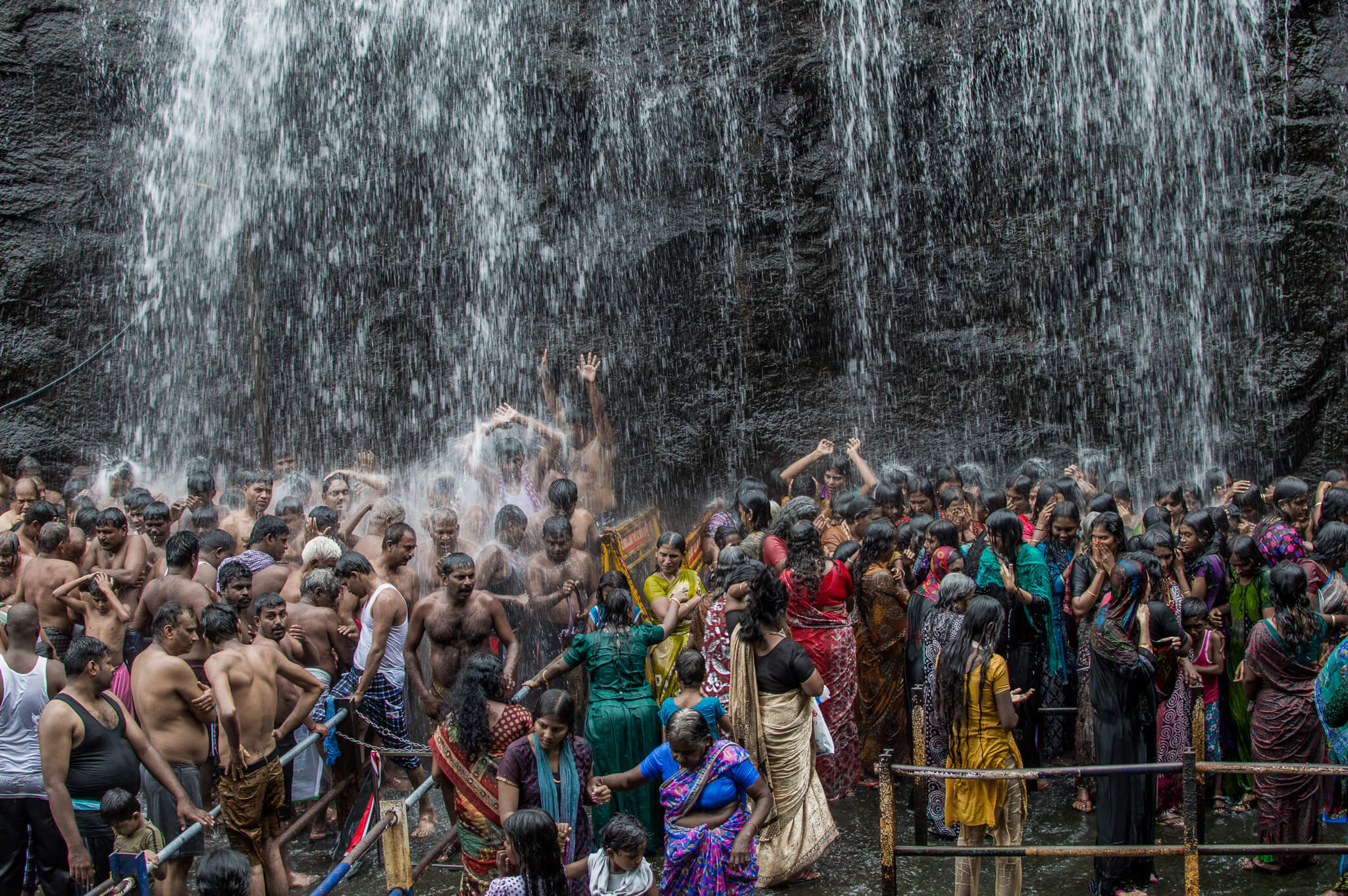 Crowd under a waterfall in Courtlam, India